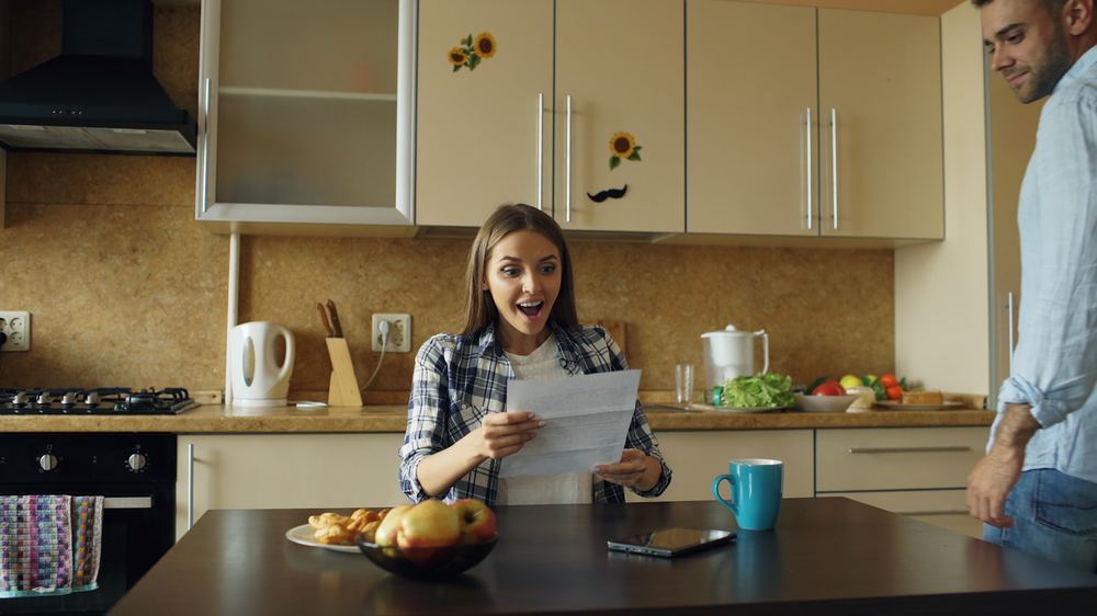 A woman at her kitchen table reading a letter