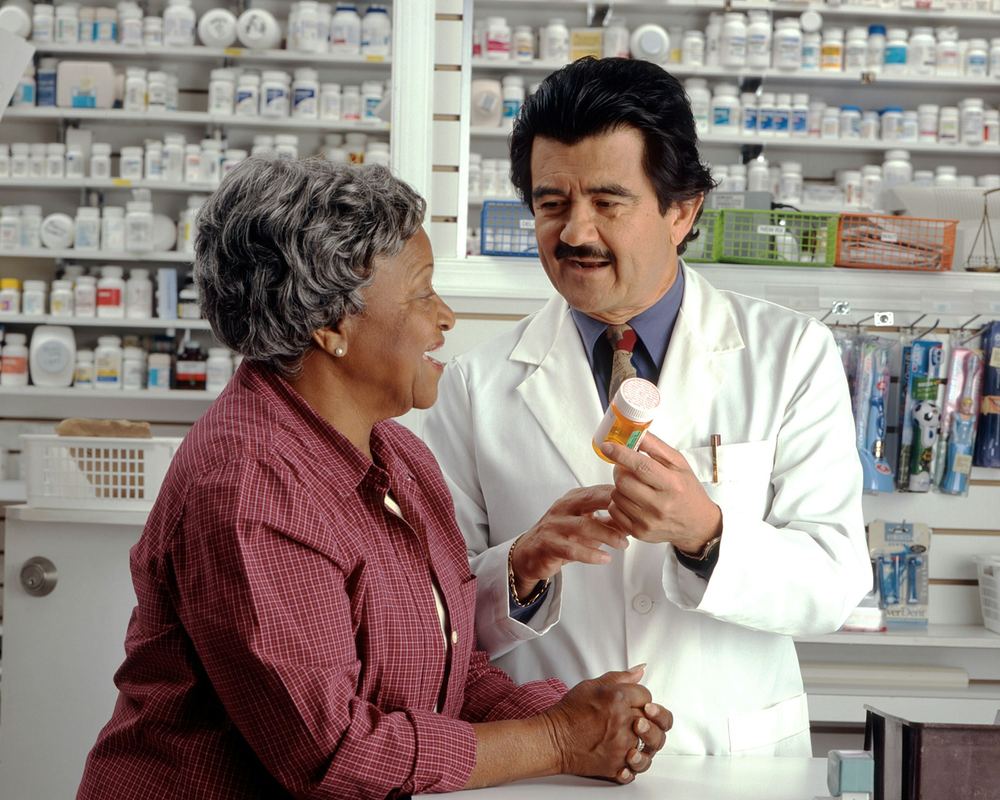 A pharmacist showing a prescription bottle to a customer